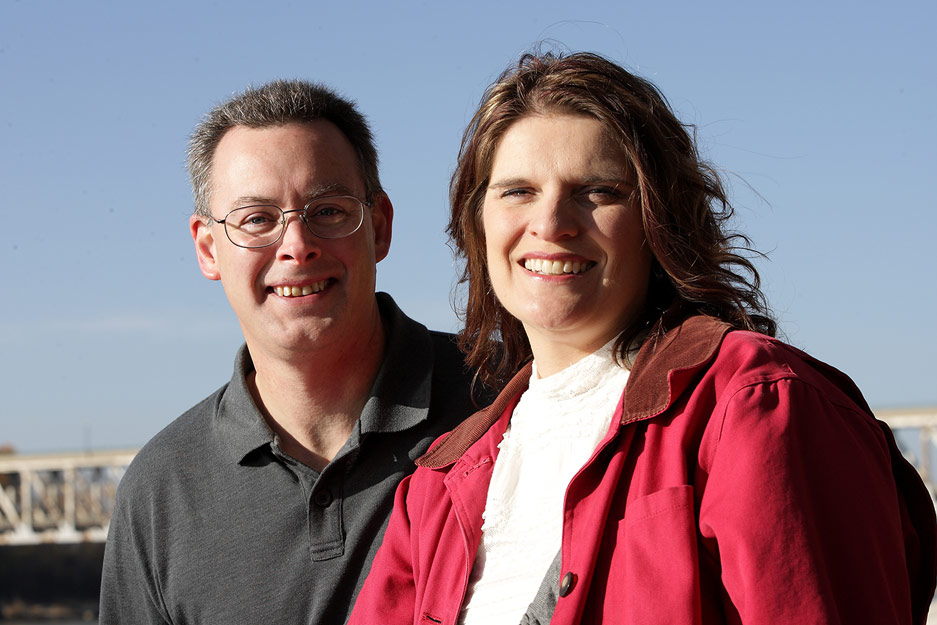 A husband and wife, wearing jackets, smiling at the camera.