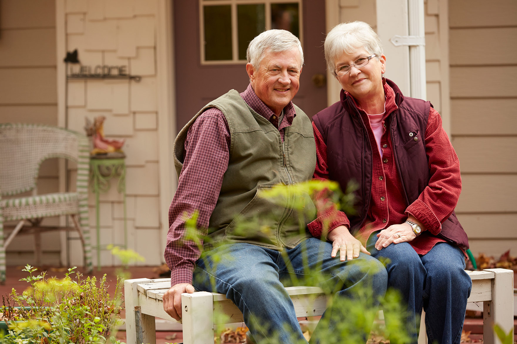 A senior couple sitting on a bench by the garden.