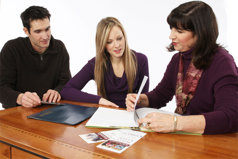 Sales Representative showing young couple documents., a common responsibility in our Sales Careers