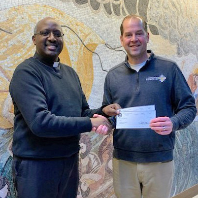 Father Gabriel in Brainerd receives a grant check from Regional Sales Director Greg Gall.