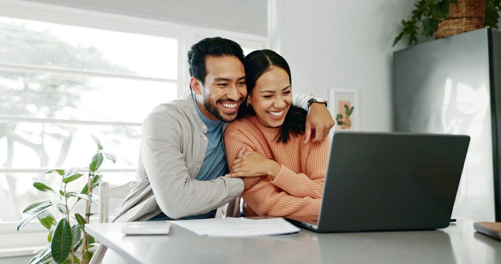 couplesmilingatcomputerweb Couple smiling at computer after scheduling an annual review with their Member Advisor