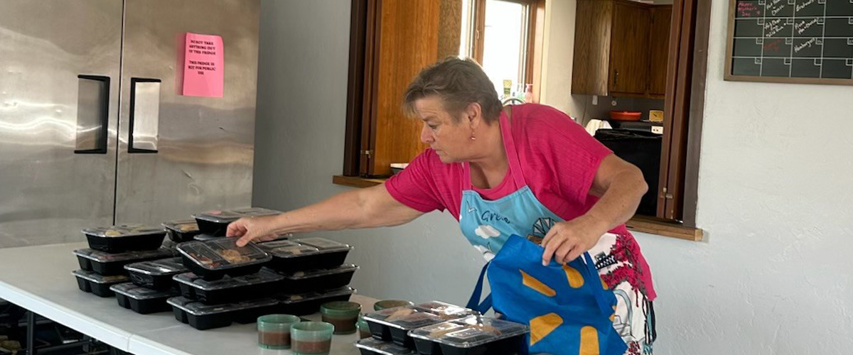 A woman packing meals for seniors in a blue bag.