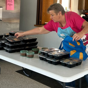 A woman packing meals for seniors in a blue bag.